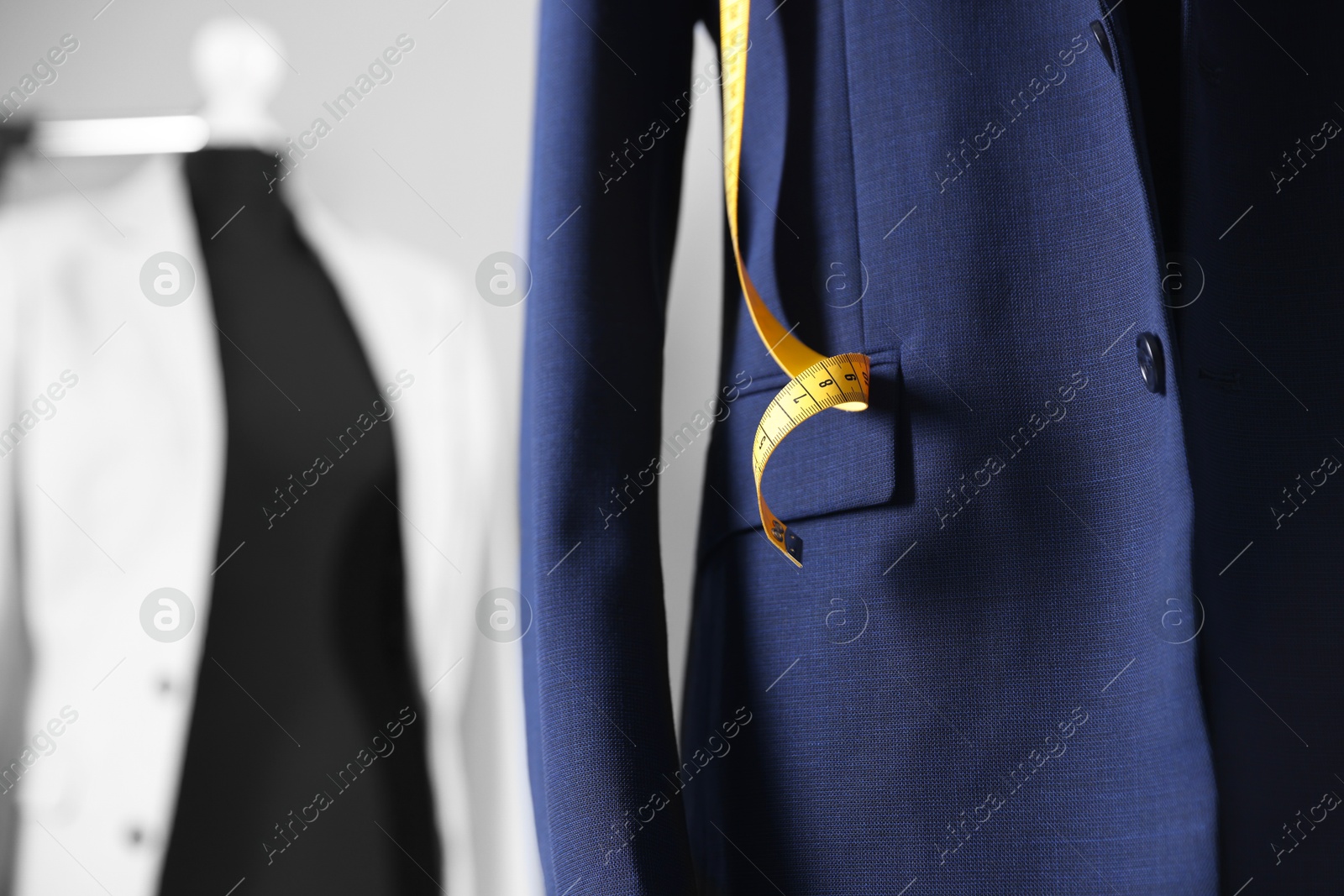 Photo of Male mannequin with jacket and measuring tape in tailor shop, closeup