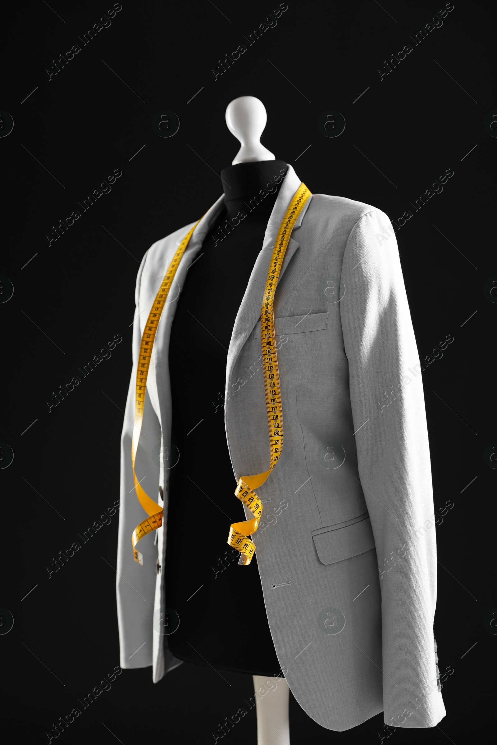 Photo of Female mannequin with gray jacket and measuring tape on dark background