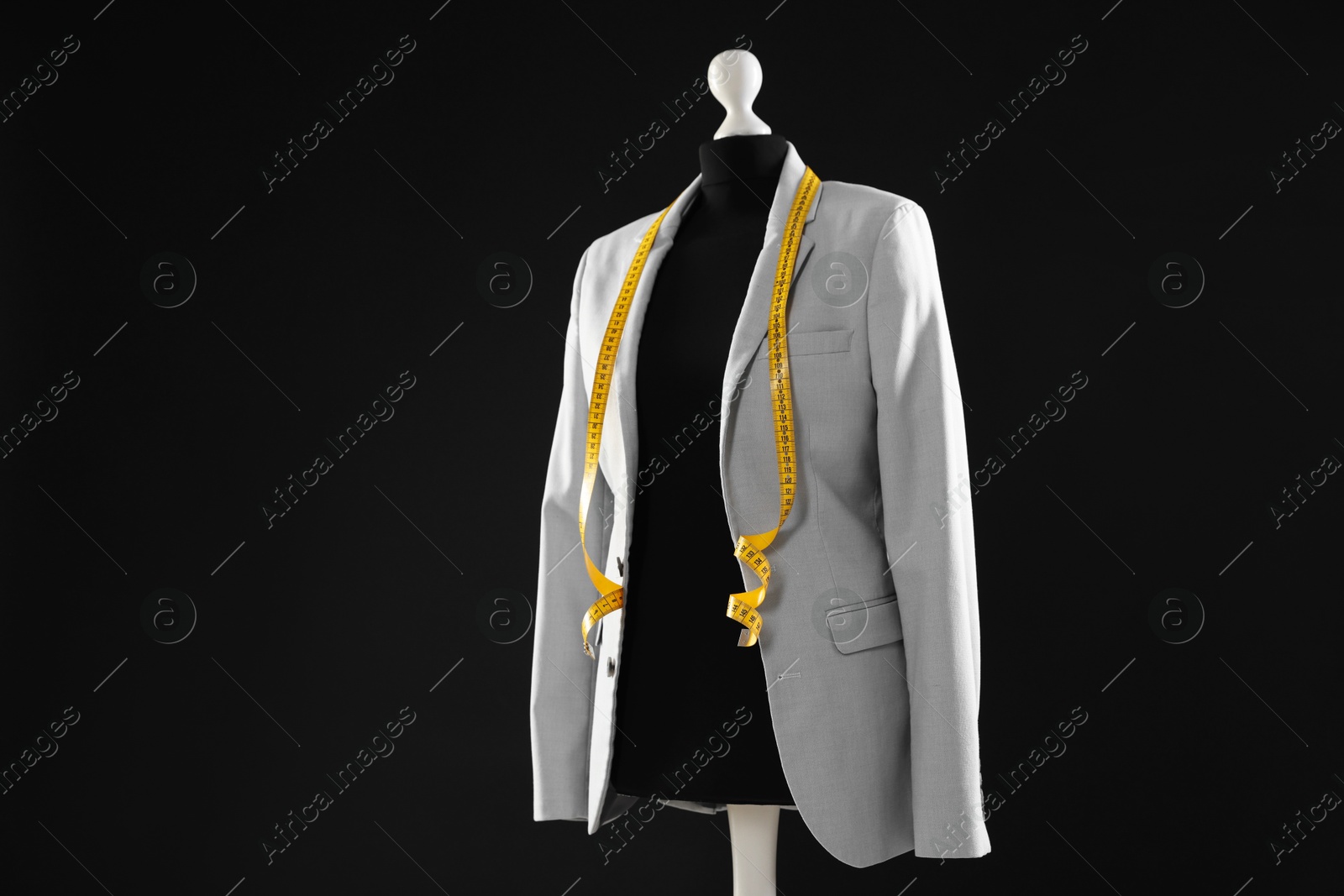 Photo of Female mannequin with gray jacket and measuring tape on dark background