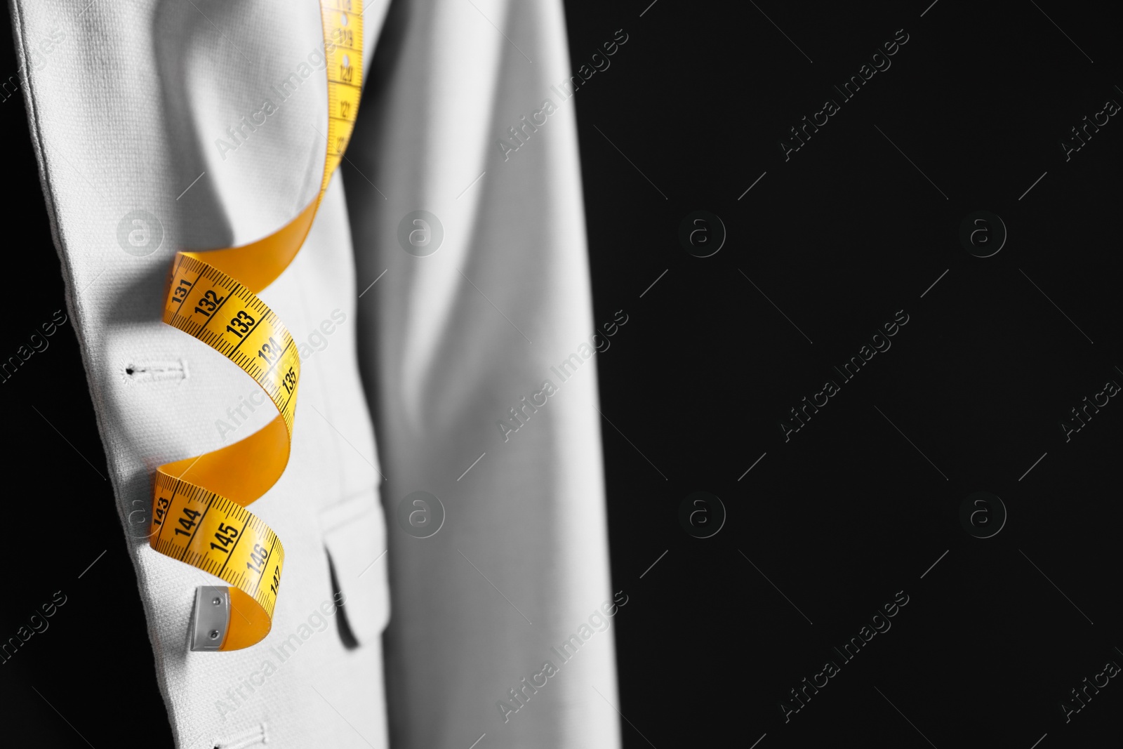 Photo of Female mannequin with gray jacket and measuring tape on black background, closeup. Space for text