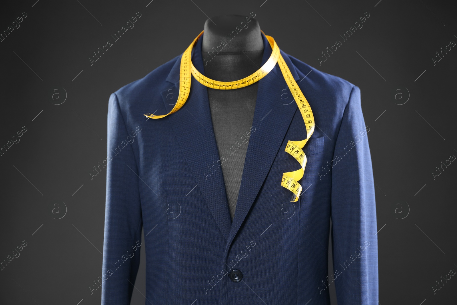 Photo of Male mannequin with jacket and measuring tape on dark background, closeup