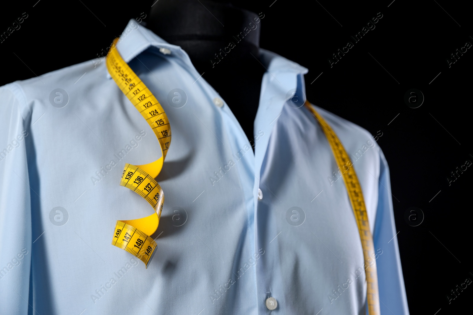 Photo of Male mannequin with shirt and measuring tape on black background, closeup