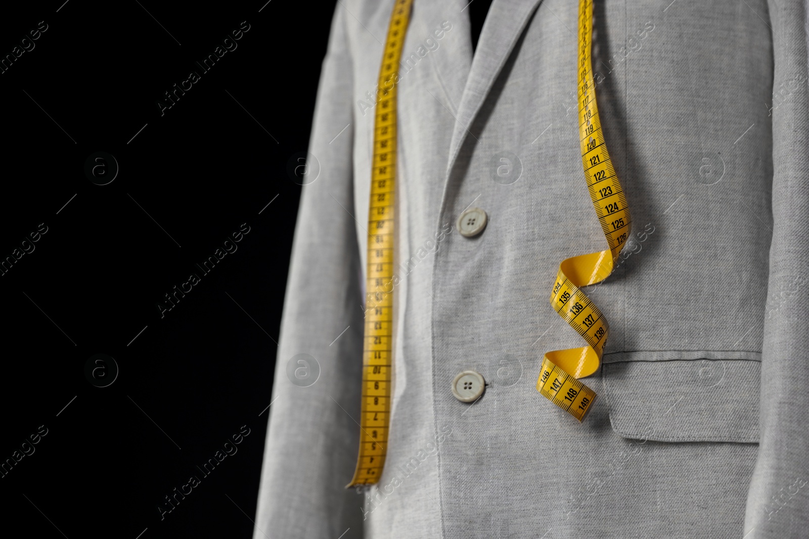 Photo of Male mannequin with jacket and measuring tape on black background, closeup. Space for text