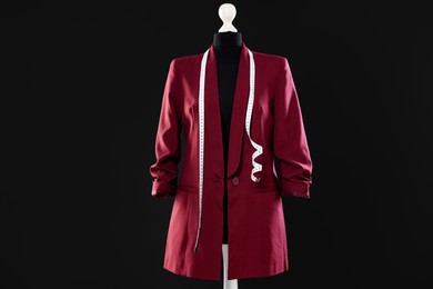 Photo of Female mannequin with stylish jacket and measuring tape on dark background