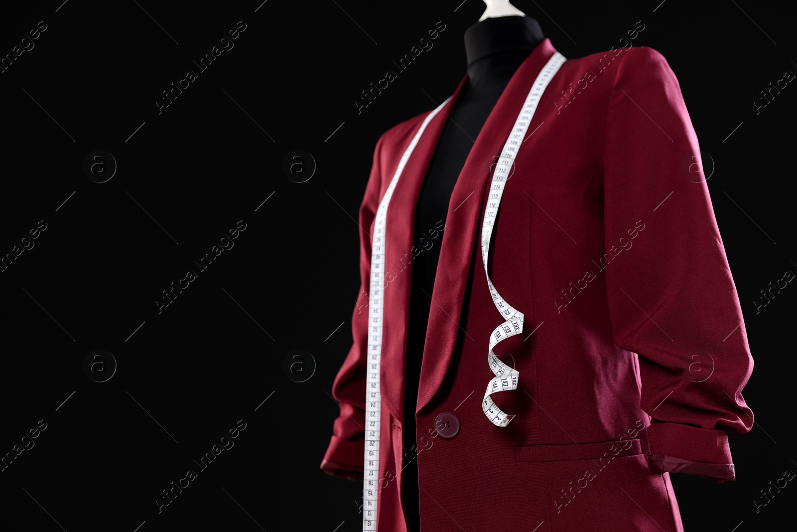 Photo of Female mannequin with stylish jacket and measuring tape on dark background, closeup. Space for text