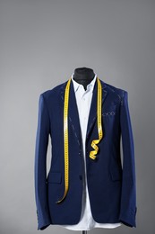 Photo of Semi-ready jacket, shirt and measuring tape on mannequin against gray background