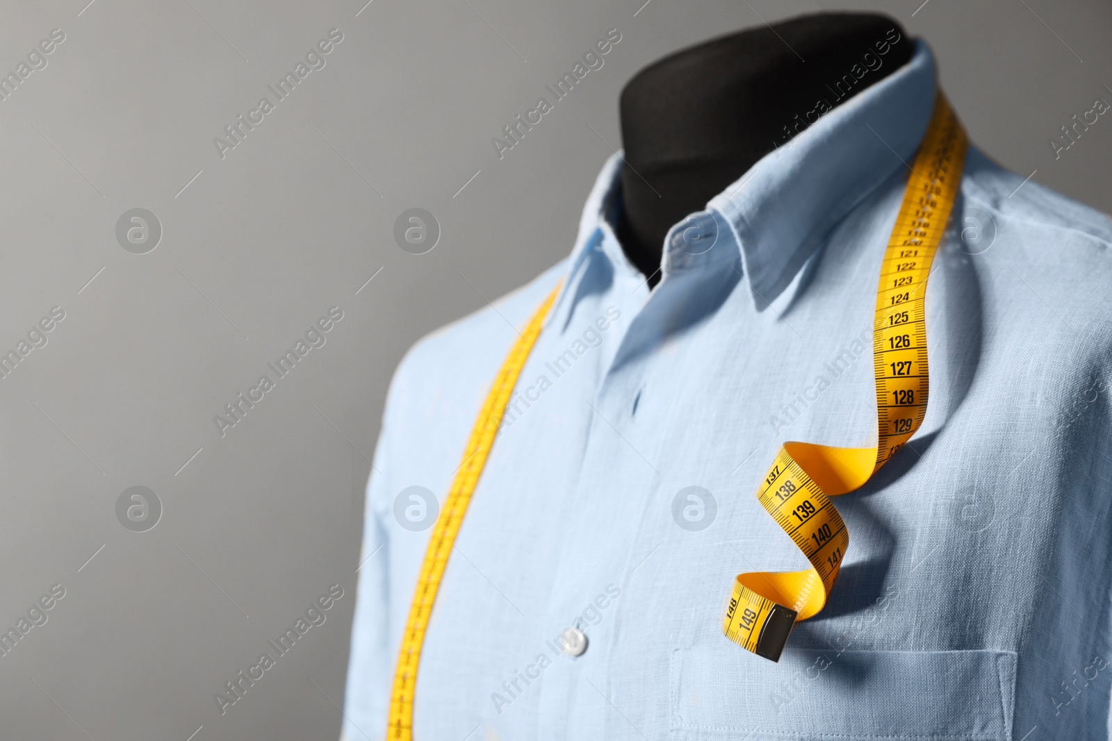 Photo of Male mannequin with shirt and measuring tape on gray background, closeup. Space for text