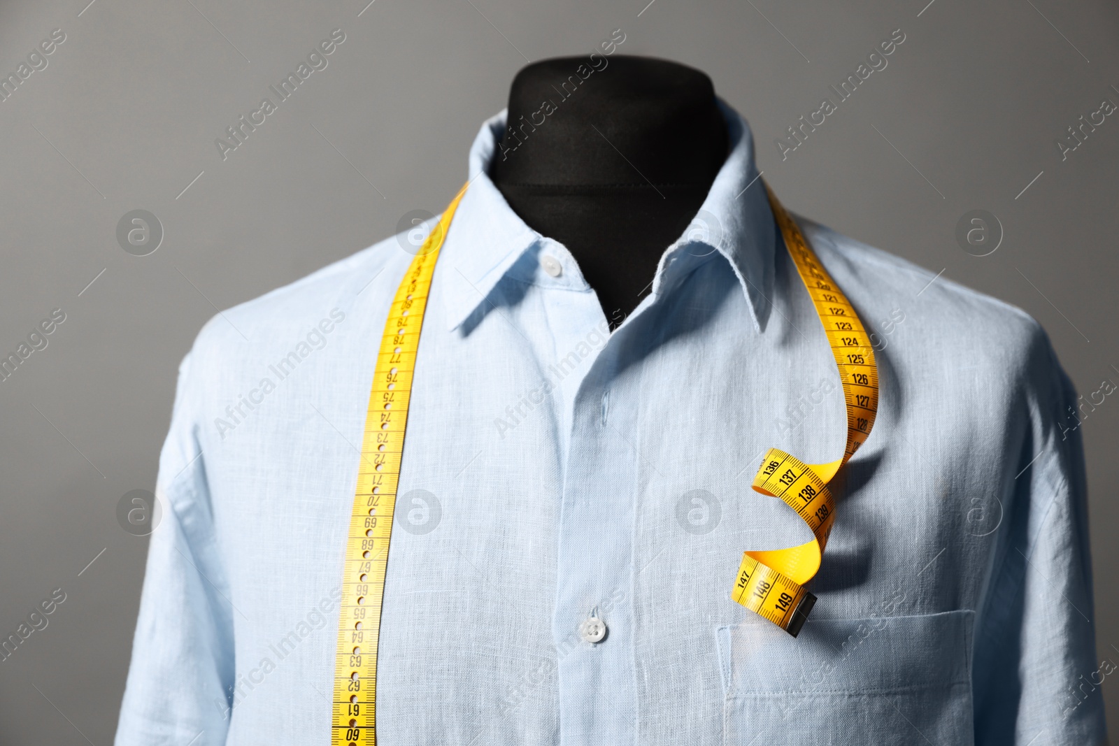 Photo of Male mannequin with shirt and measuring tape on gray background, closeup