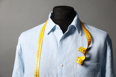 Photo of Male mannequin with shirt and measuring tape on gray background, closeup