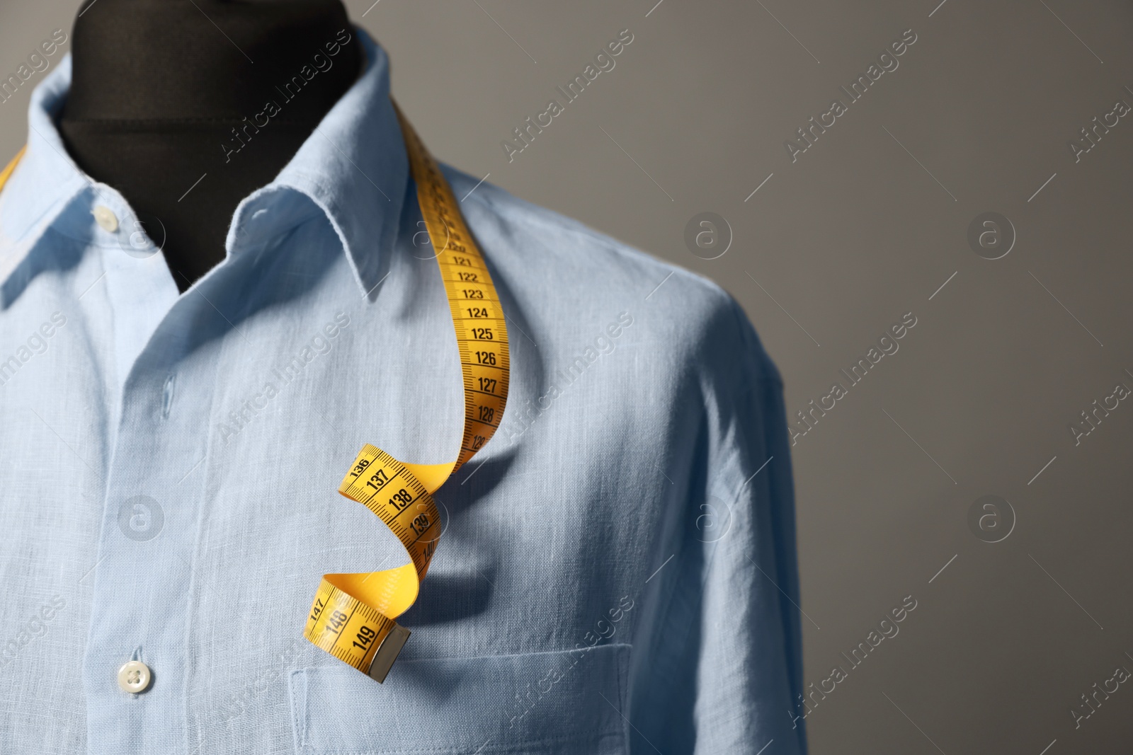 Photo of Male mannequin with shirt and measuring tape on gray background, closeup. Space for text