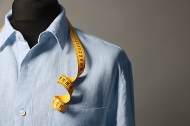 Photo of Male mannequin with shirt and measuring tape on gray background, closeup. Space for text