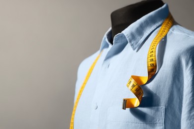 Photo of Male mannequin with shirt and measuring tape on gray background, closeup. Space for text