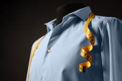 Photo of Male mannequin with shirt and measuring tape on dark background, closeup