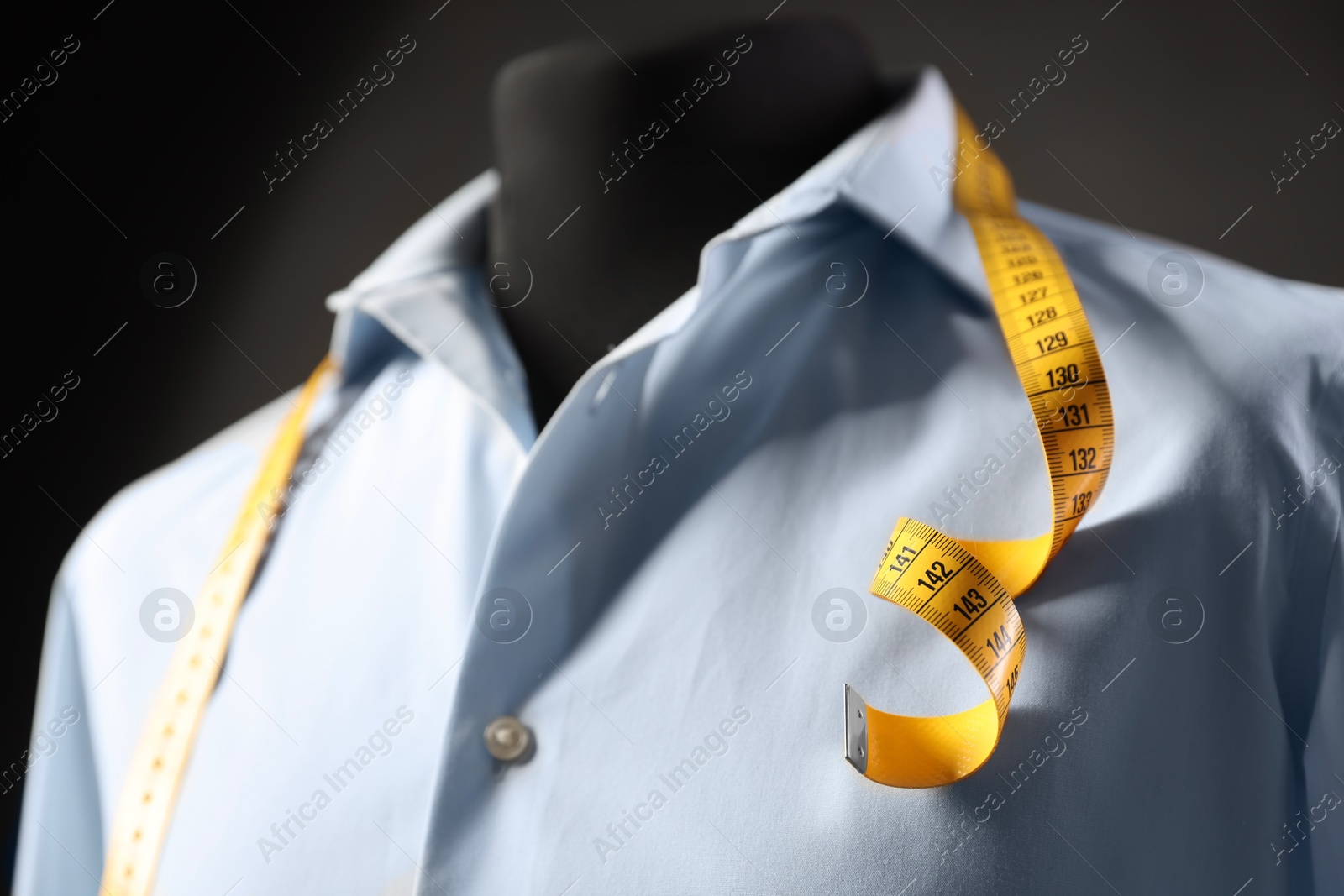 Photo of Male mannequin with shirt and measuring tape on dark background, closeup