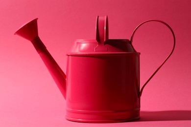 Photo of Metal watering can on bright pink background