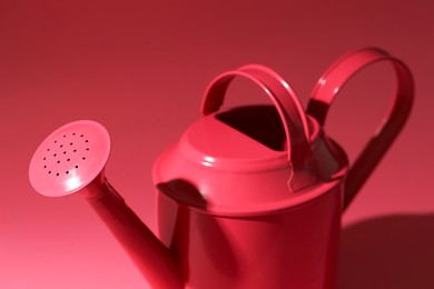 Photo of Metal watering can on bright pink background, closeup