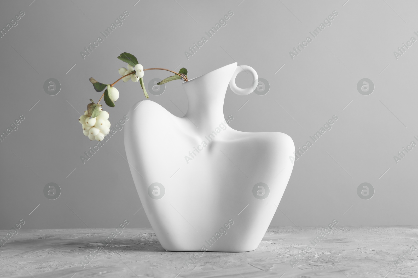 Photo of Stylish vase with snowberry branch on grey table