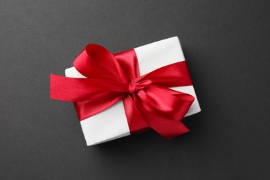 Photo of Gift box with red bow on black background, top view