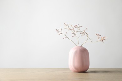 Photo of Stylish vase with beautiful branches on wooden table, space for text