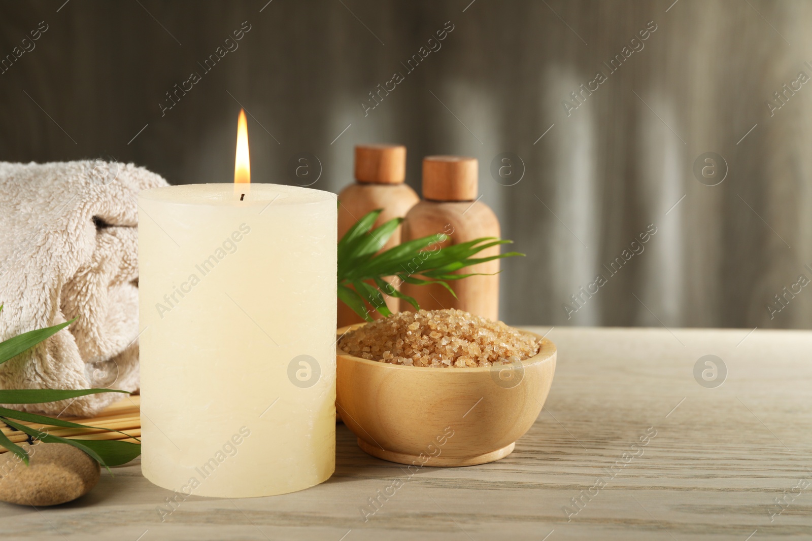 Photo of Spa composition with burning candle on wooden table, space for text