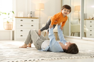 Photo of Mother playing her happy little son at home