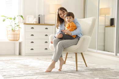 Photo of Happy mother with her little son sitting on armchair at home. Space for text