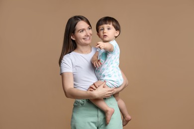 Photo of Happy mother with her little son on beige background