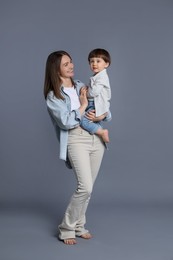 Photo of Happy mother with her little son on grey background