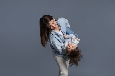 Photo of Happy mother playing with her little son on grey background