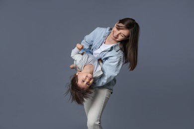 Photo of Happy mother playing with her little son on grey background