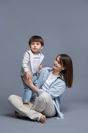 Photo of Happy mother with her little son on grey background