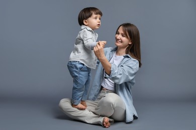 Photo of Happy mother with her little son on grey background