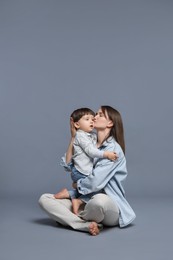 Photo of Mother kissing her little son on grey background. Space for text