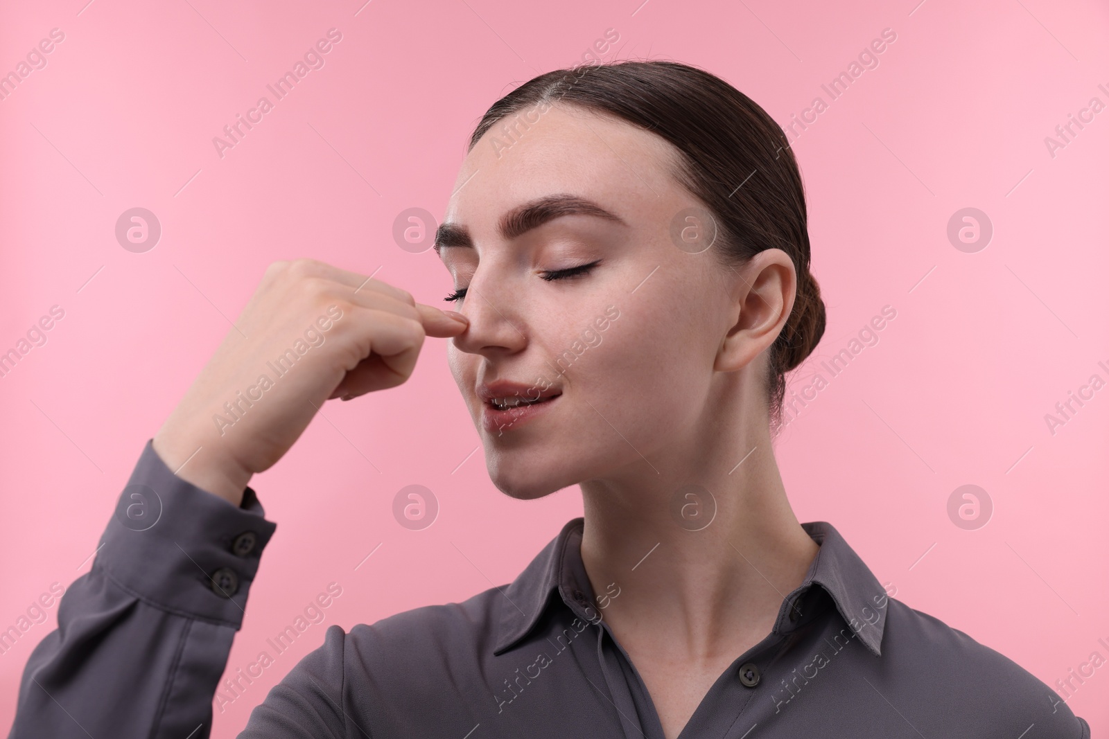 Photo of Woman touching her nose on pink background