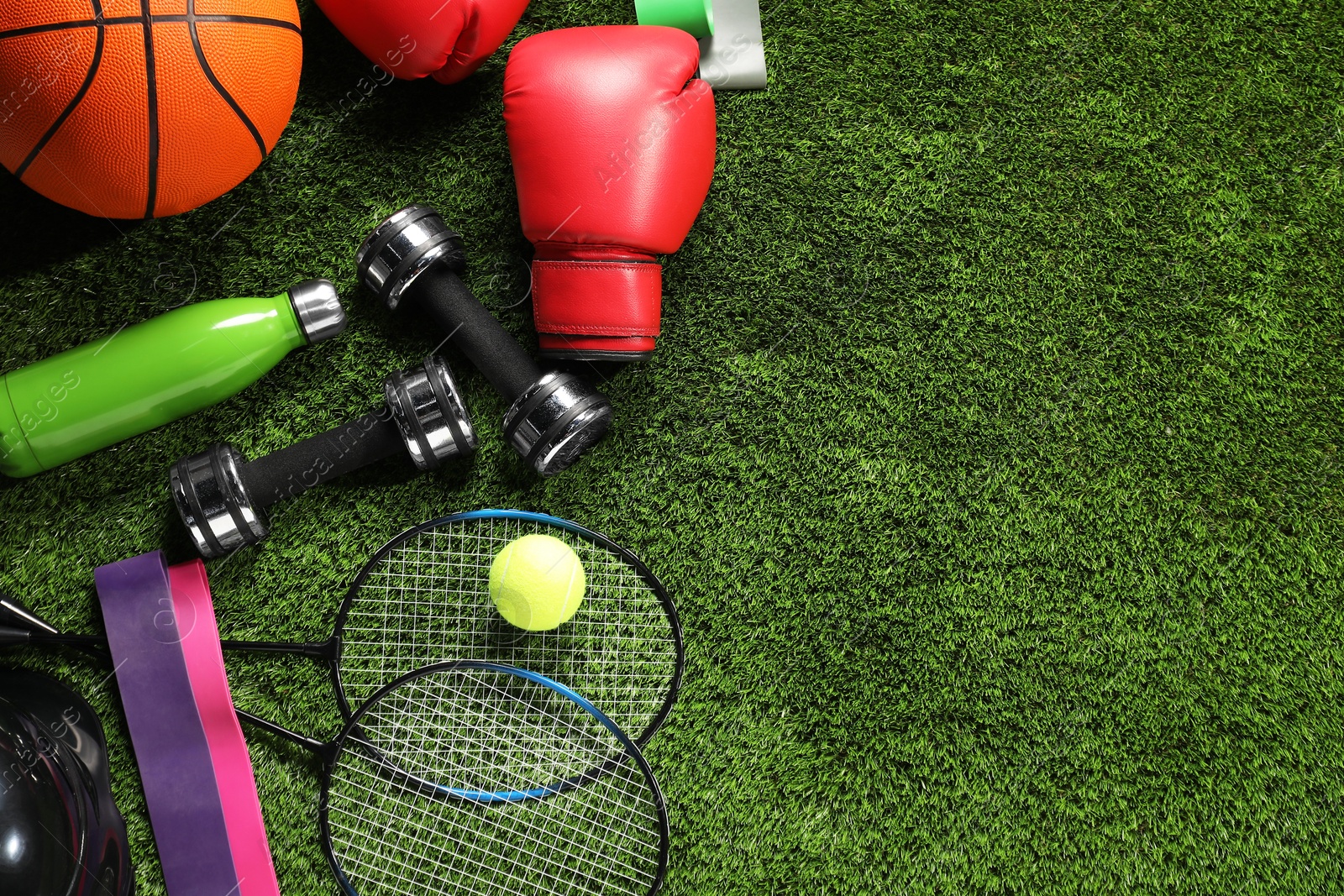 Photo of Different sports equipment on artificial grass, flat lay. Space for text