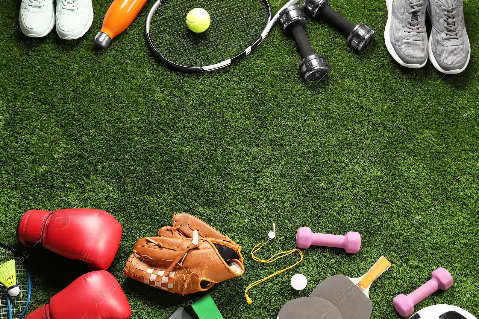 Photo of Different sports equipment on artificial grass, flat lay. Space for text