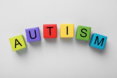 Photo of Word Autism made with colorful cubes on grey background, flat lay