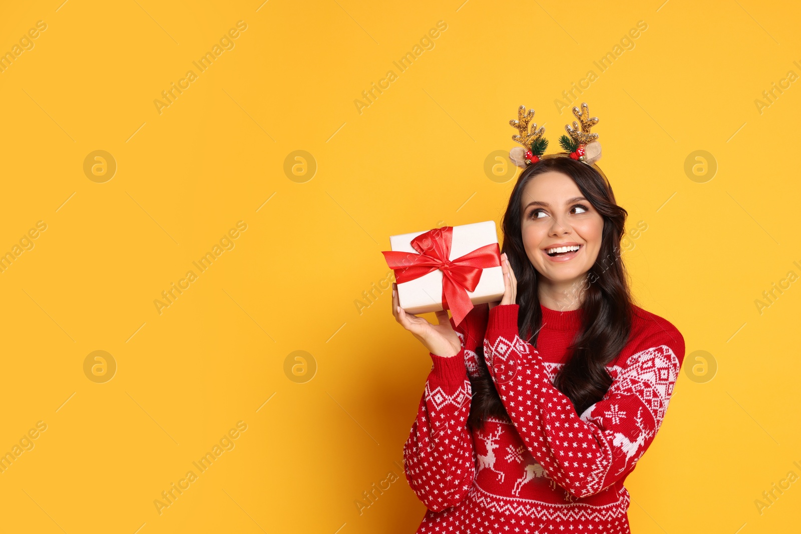 Photo of Happy woman with Christmas gift on yellow background, space for text