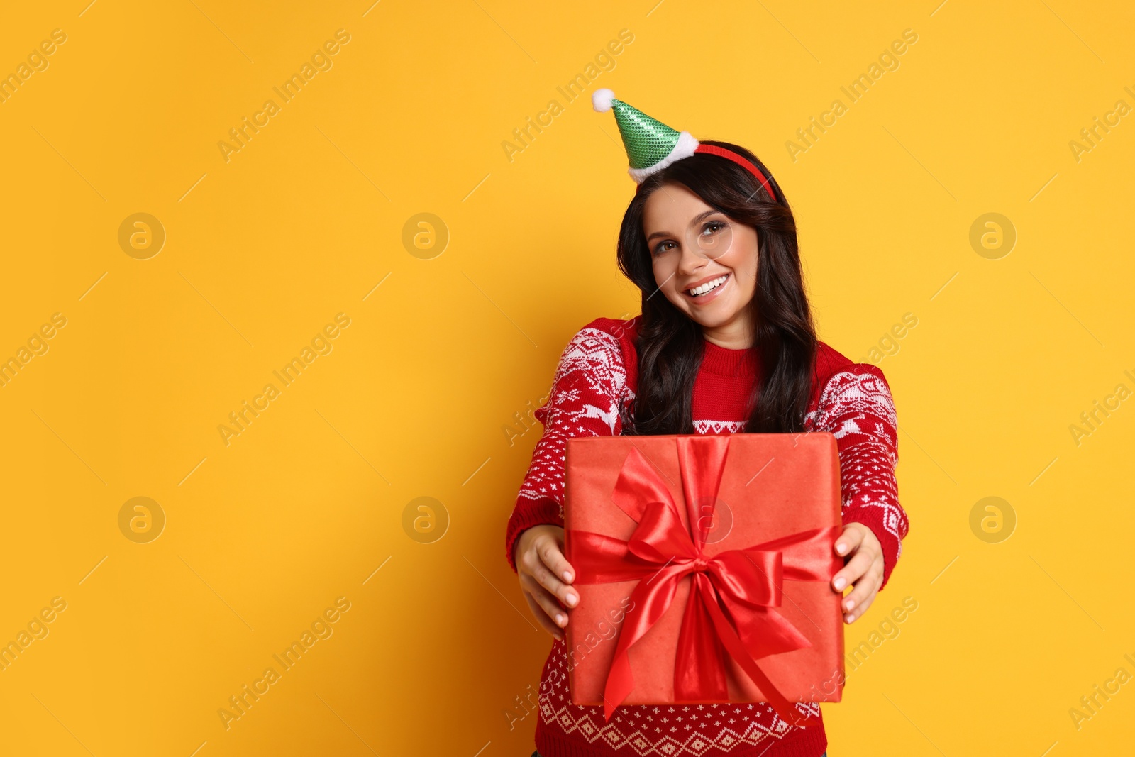 Photo of Happy woman with Christmas gift on yellow background, space for text