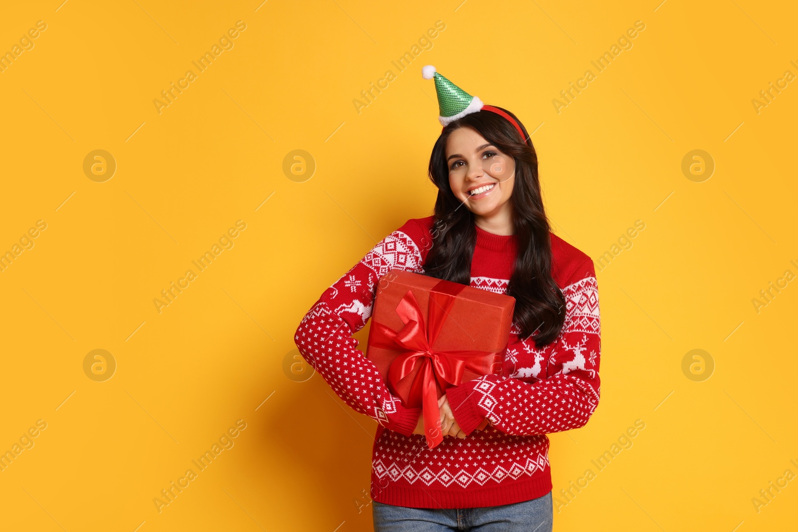 Photo of Happy woman with Christmas gift on yellow background, space for text