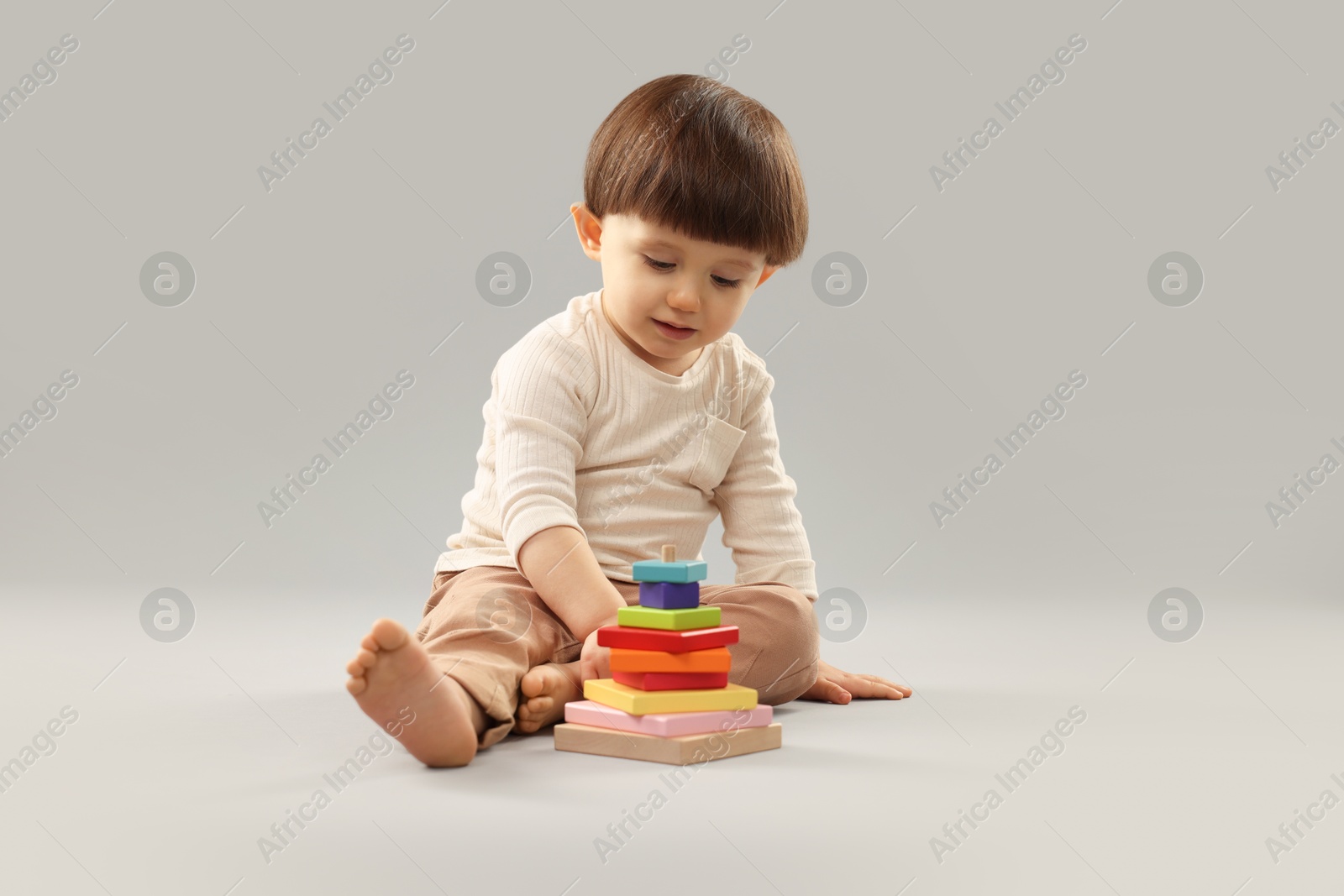 Photo of Cute little boy playing on grey background