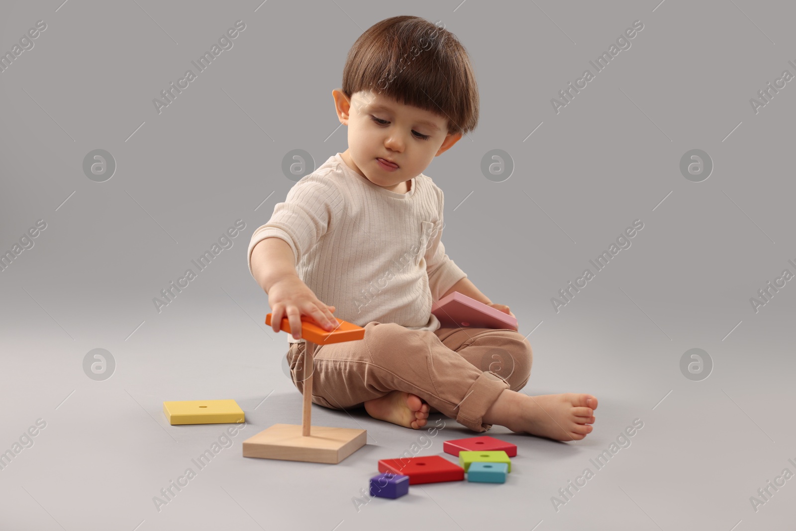 Photo of Cute little boy playing on grey background