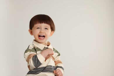 Photo of Emotional little boy on light grey background. Space for text