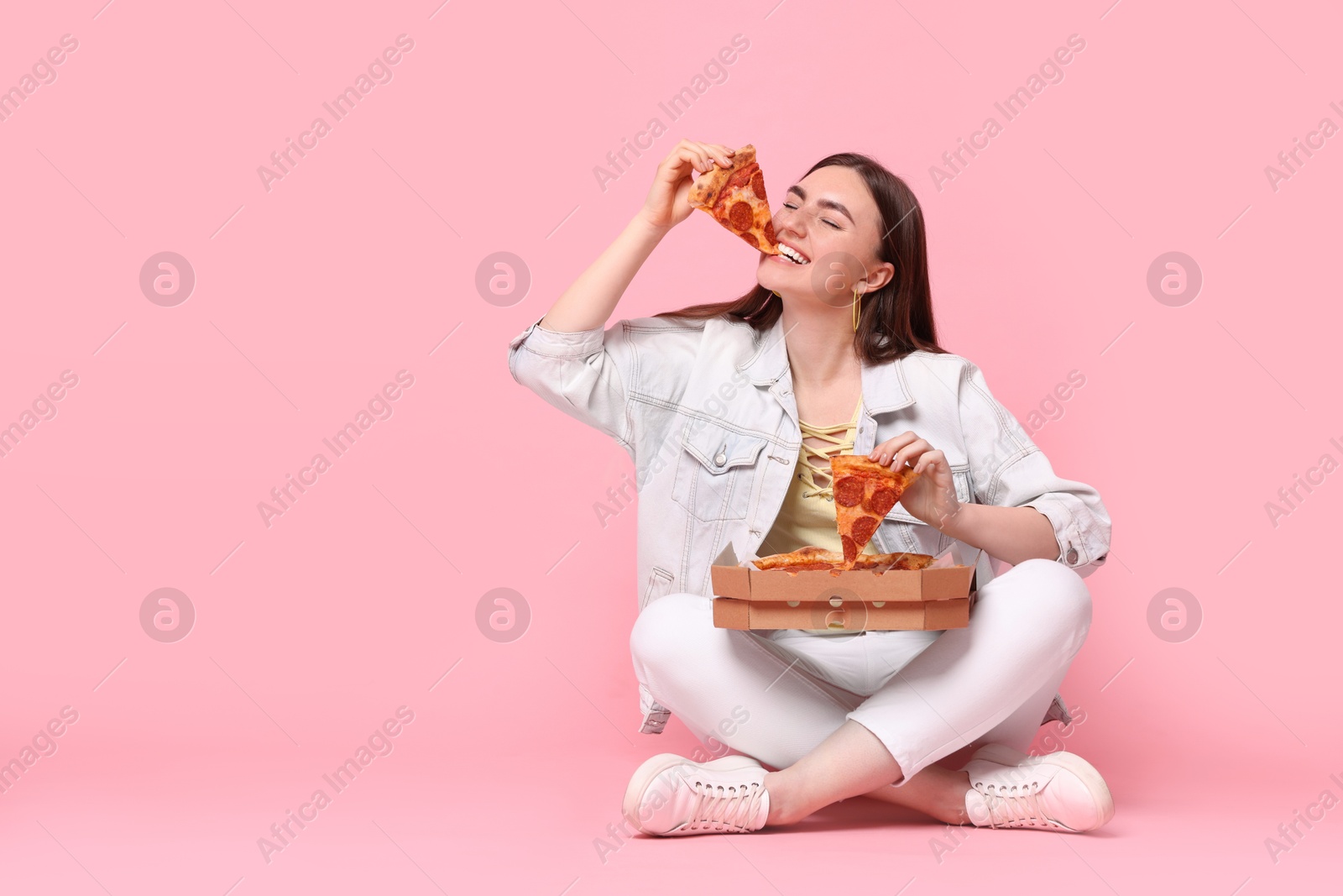 Photo of Beautiful woman with delicious pizza on pink background, space for text