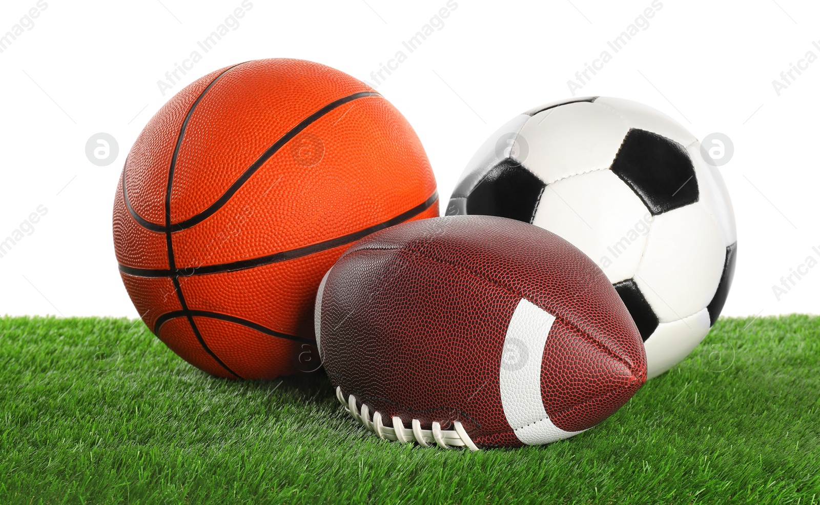 Photo of Different balls on artificial grass isolated on white. Sport equipment