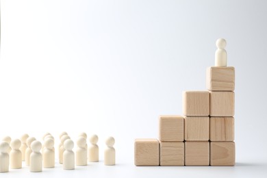 Human figures in front of stacked wooden blocks with one figure on top against white background. Competition concept