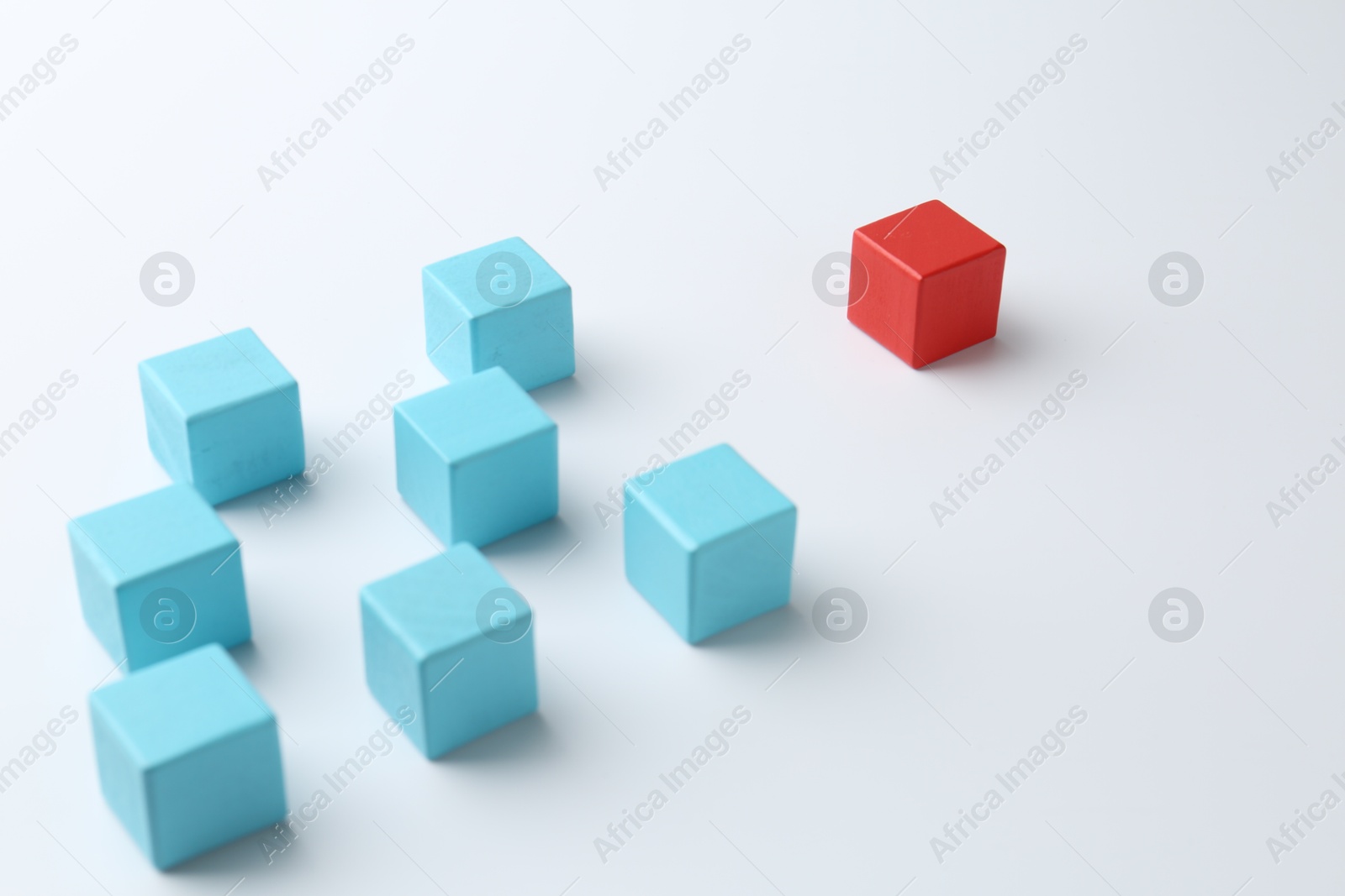 Photo of Red cube in front of blue ones on white background. Competition concept