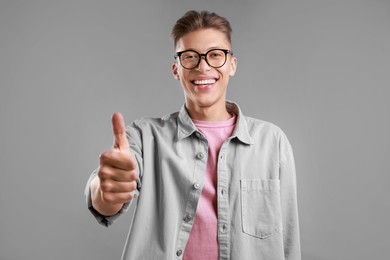 Photo of Happy man showing thumbs up on grey background. Like gesture