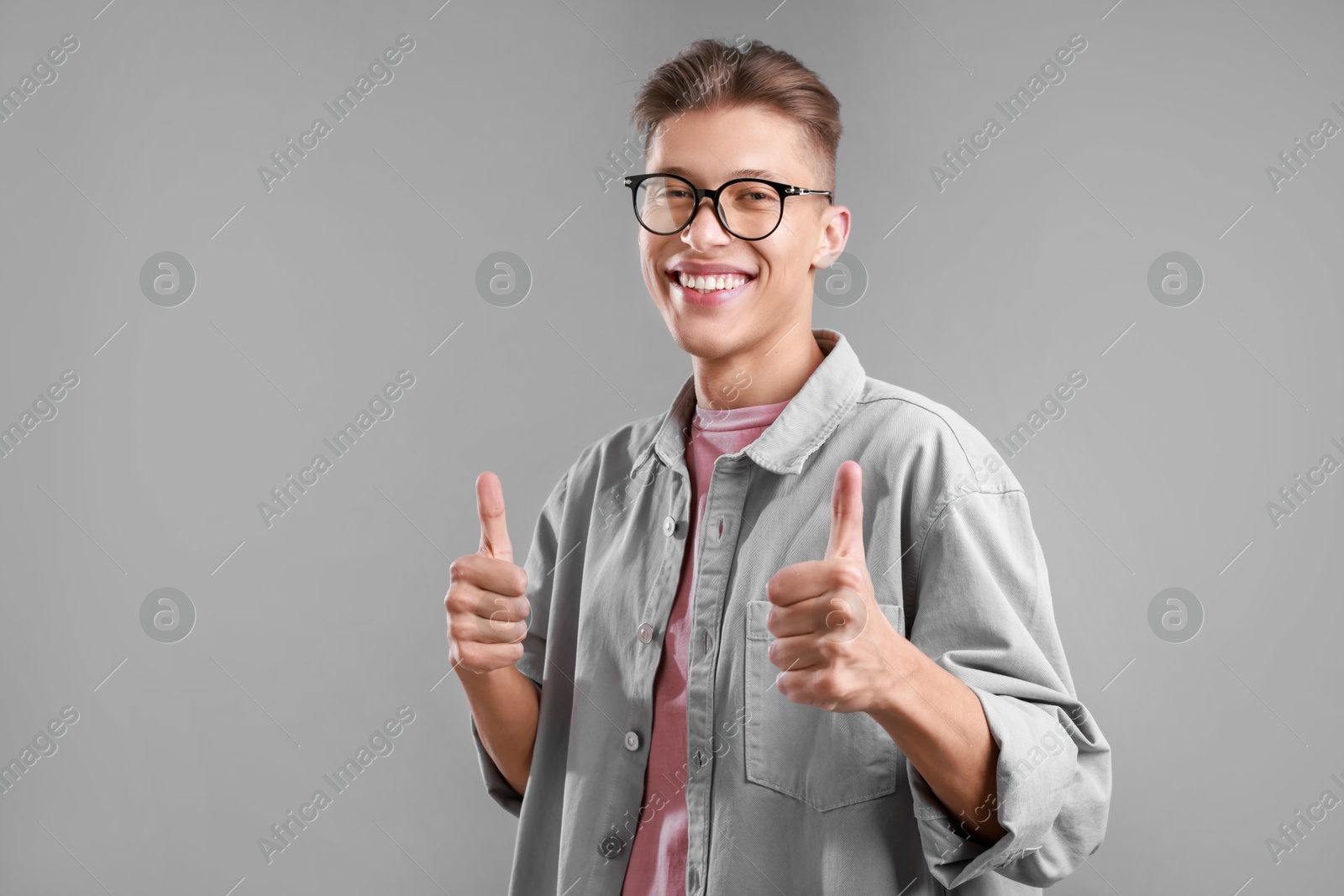 Photo of Happy man showing thumbs up on grey background, space for text. Like gesture