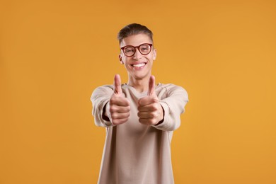 Happy man showing thumbs up on orange background. Like gesture